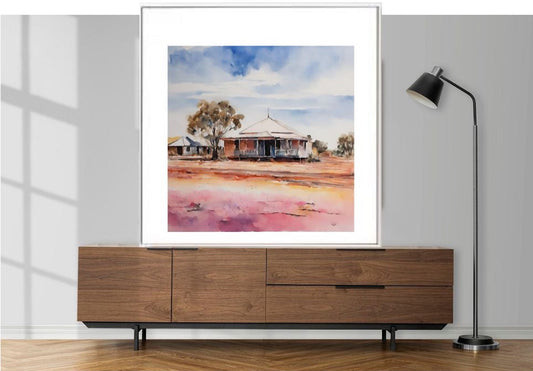 Framed artwork framed in white of a rural landscape Darwin Australia on a wooden cabinet with a lamp.