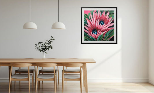 Framed artwork of surreal pink flowers on a wall above a dining table.