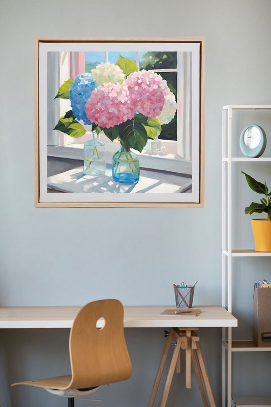 pink, blue and white hydrangeas in glass vases on table near window, art print framed in wood and hanging on wall above desk.