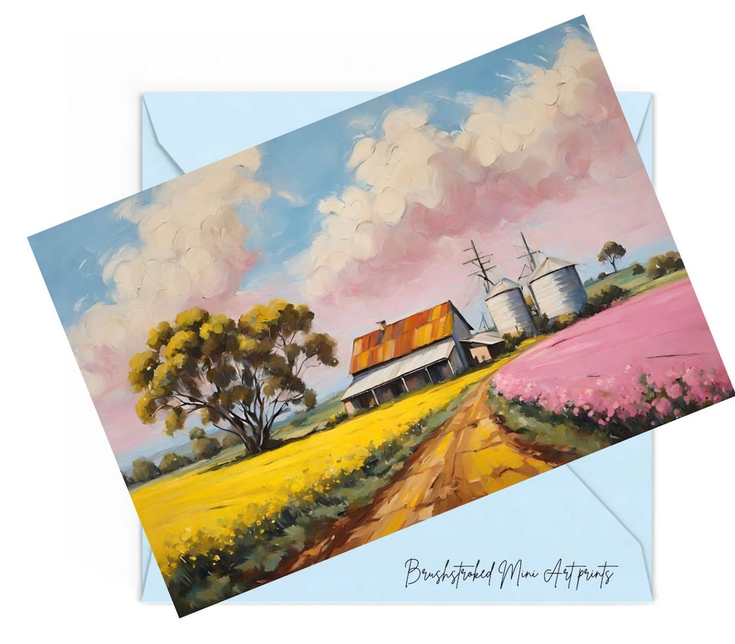 art print of a rural landscape with a house, trees, and pink sky on top of an envelope