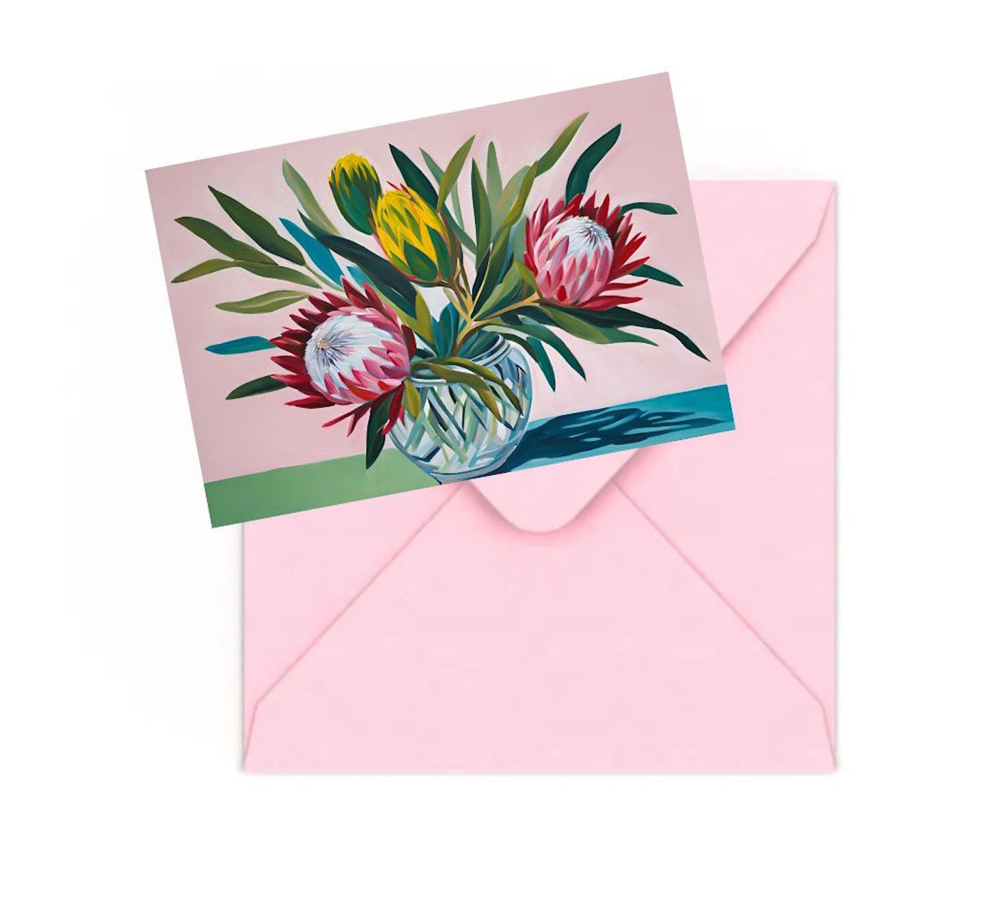 Mini art print of colourful proteas flowers in a glass bowl on table, on top of a Pink envelope