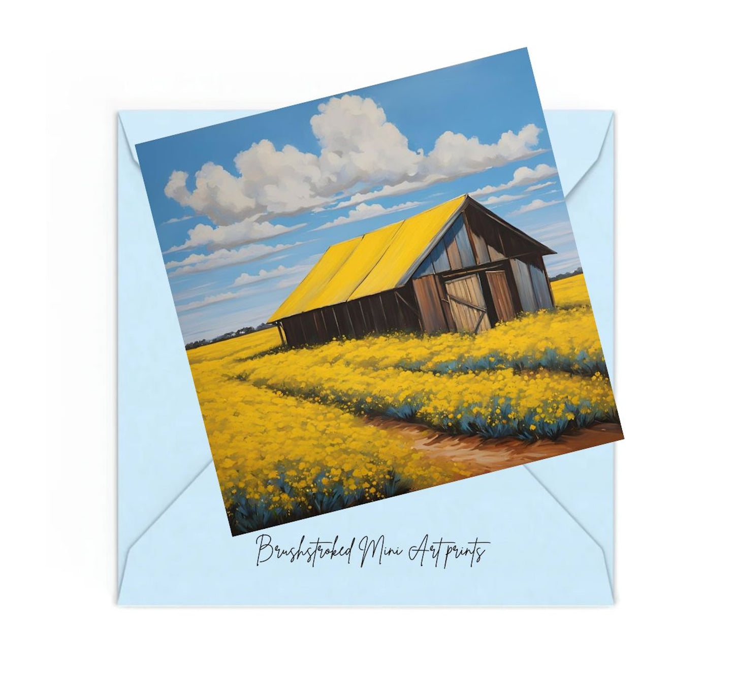 Mini art print of an old farmhouse with canola fields blue skies on top of a blue envelope