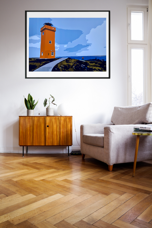 orange lighthouse on top of cliff blue skies art print framed in black hanging on wall.
