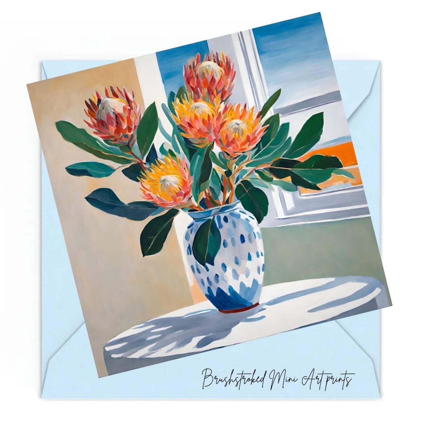 pink and orange proteas flowers in blue and white ceramic vase on white table near window mini art print.