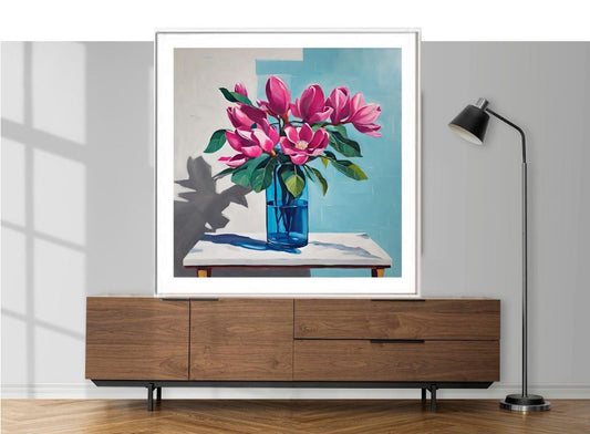 Framed artwork of pink flowers in a blue vase on a wall above a wooden cabinet.