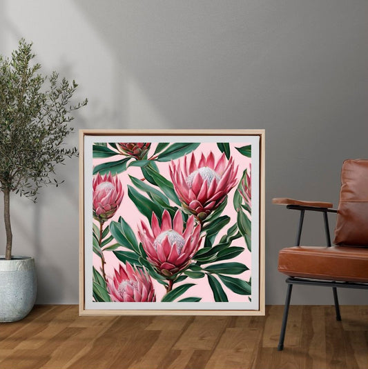 Pink proteas with green leaves framed art on floor next to plant and chair