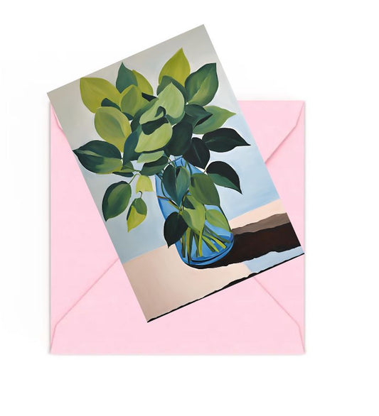 Mini art print with green leaves in blue glass vase on top of a Pink envelope