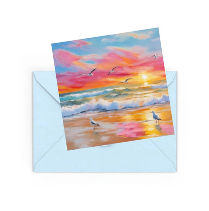 mini art print of a colourful beach sunset with waves and seagulls, sitting on top of a Blue envelope for posting.