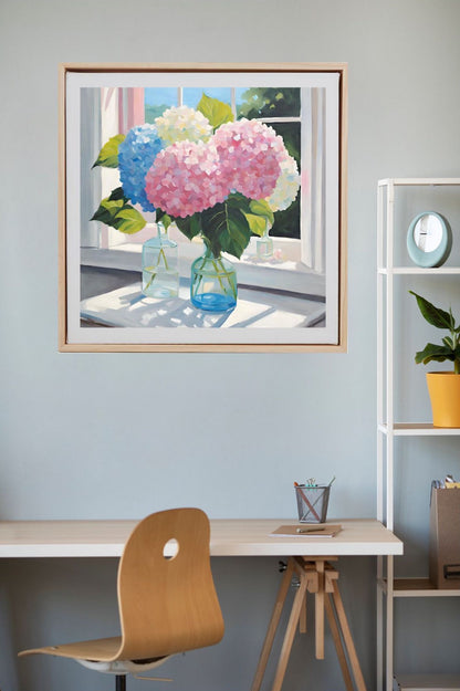 pink, blue and white hydrangeas in glass vases on table near window, art print framed in wood and hanging on wall above desk.