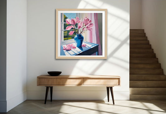 Framed artwork of a window scene with pink flowers on a wall above a wooden console table.