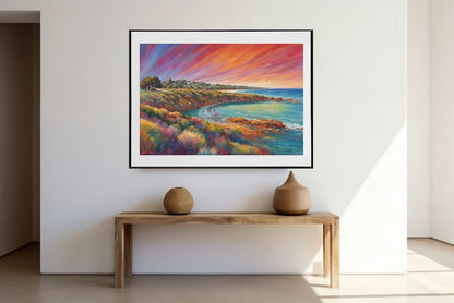 Framed colourful seascape sunset painting on a wall above a wooden console table with two ceramic pots.