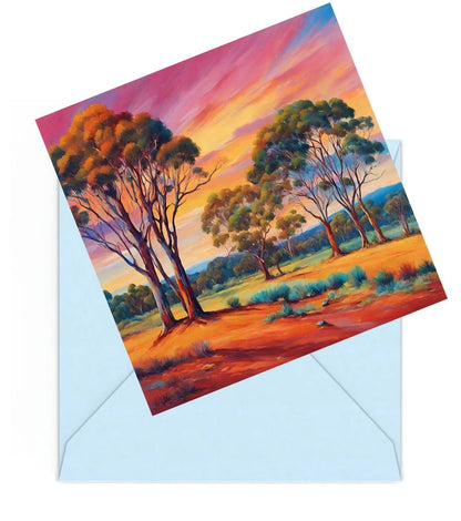 Mini art print of an australian colourful sunset landscape with gum trees, on top of a Blue envelope.