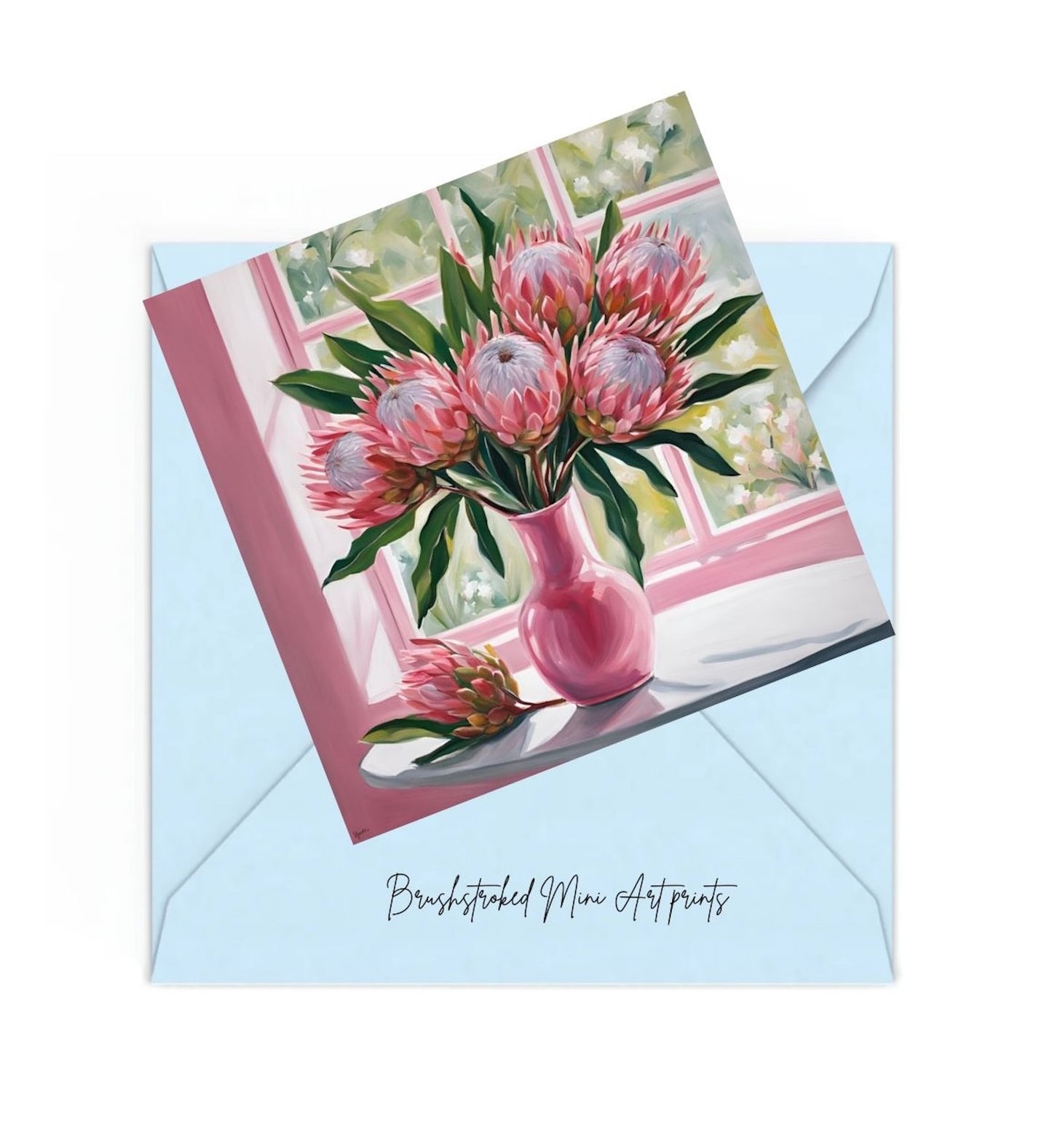 mini art print of pink proteas in pink vase on table near window on top of a blue envelope